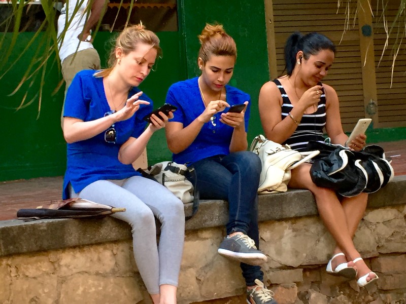 Young Cubans using one of Havana’s recently created public Wi-Fi zones, where the equivalent of $2 buys an hour of internet access. The zones have opened a window to the web for thousands of Cubans who lacked other access before. Photo by: Jon Elliston